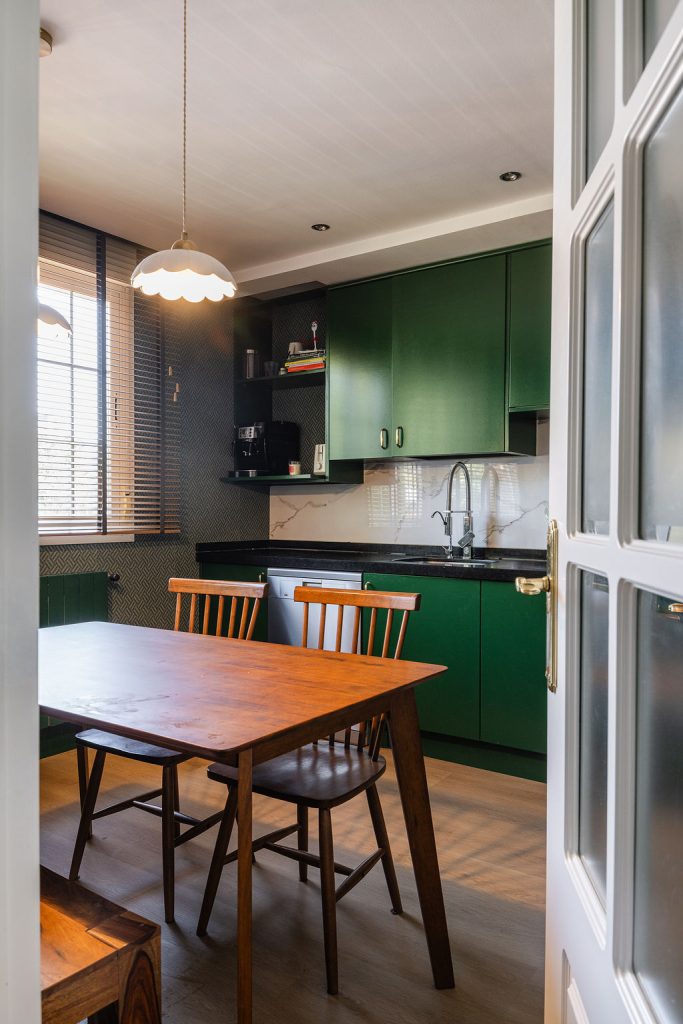 Cocina verde con mesa de madera y papel pintado geométrico